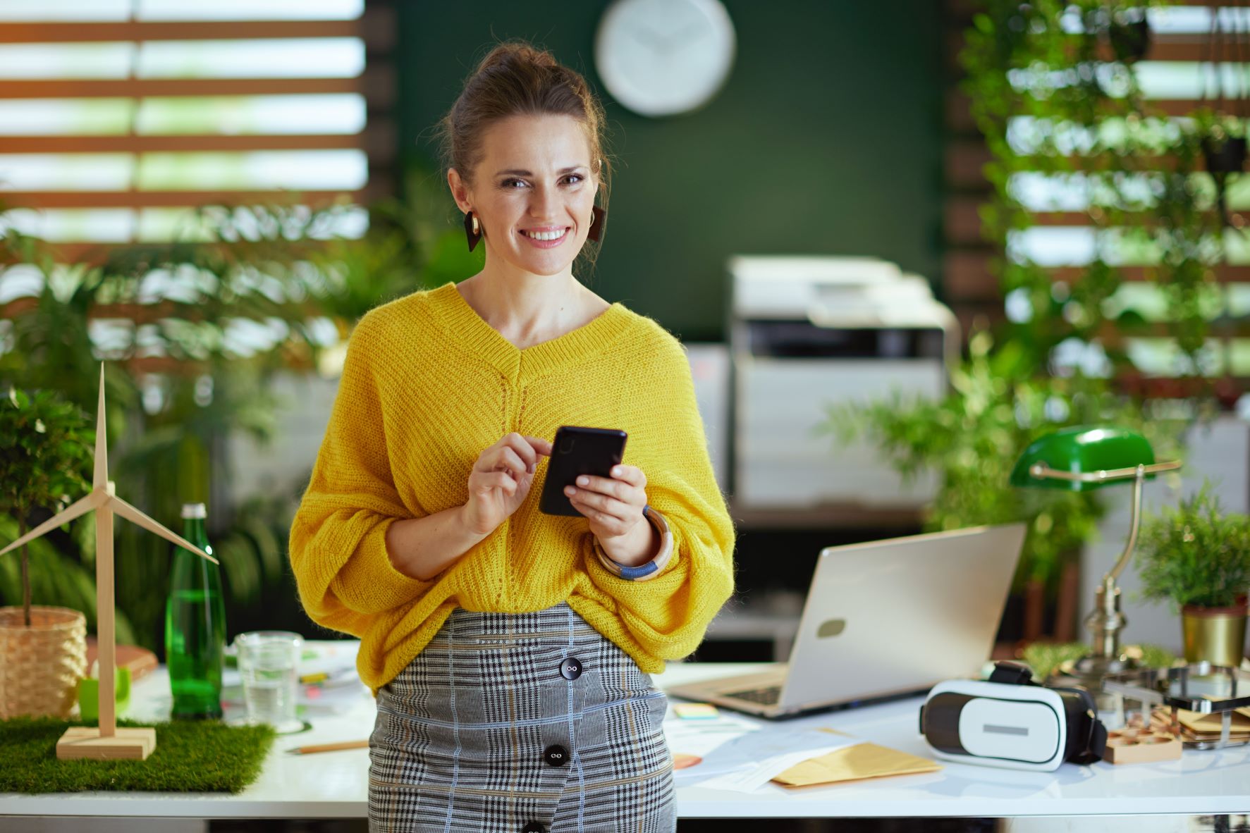 woman holding phone green background plants resized
